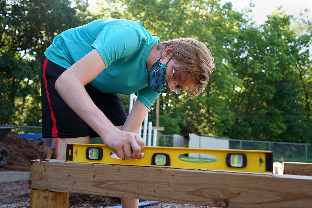 Julian Schmidt, 15 uses a level to check if the log is balanced on Thursday at Derby Ridge Elementary